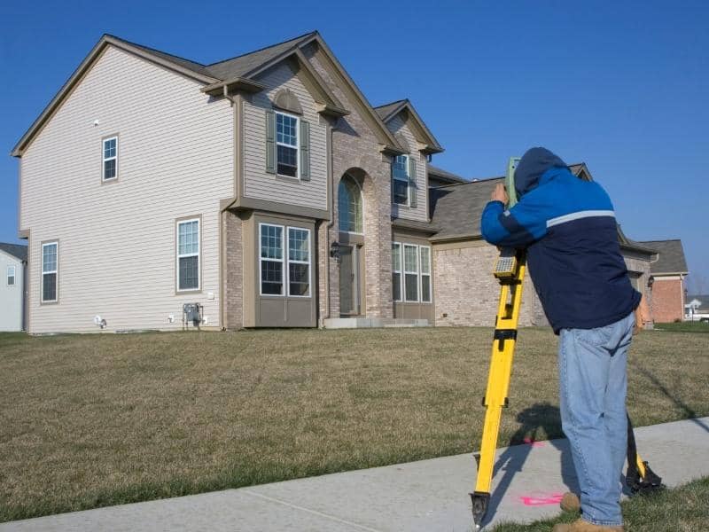 Land surveyor measuring a residential property during a routine land survey
