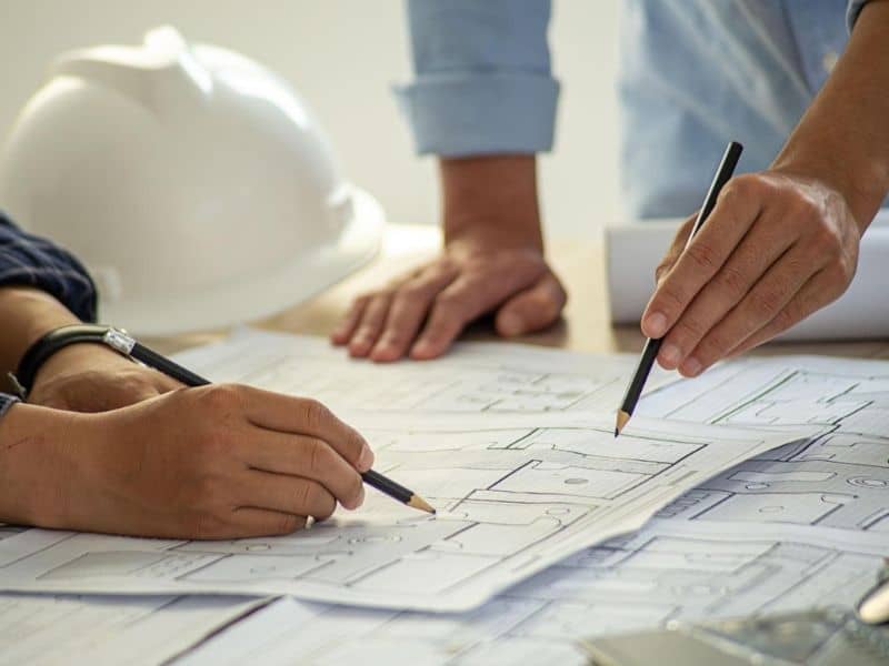 Two professionals reviewing a property plat map and survey documents to understand lot boundaries and land details