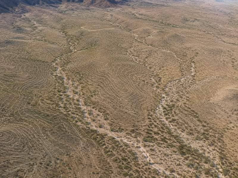 Aerial view of shallow branching dry washes crossing open desert land planned for development.